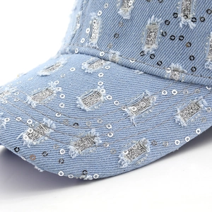 Macro shot of distressed denim baseball cap with silver sequins and frayed hole details