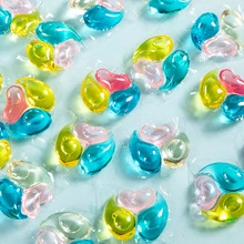 Close-up of multi-colored concentrated detergent pods in blue, yellow and pink on blue background