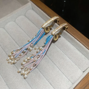 Detailed close-up of pearl tassel earrings with zircon studs in a velvet jewelry box