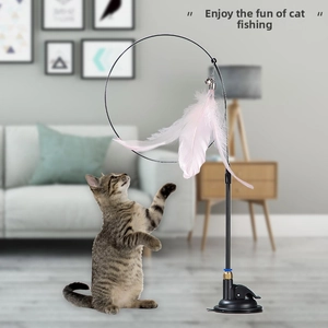 Cat toy with pink feather pendant and suction cup base on grey modern floor