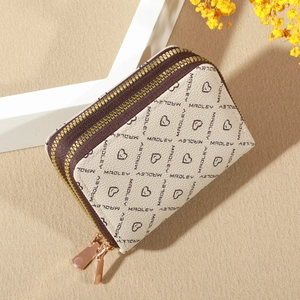 Detail of cream leather coin purse with heart patterns and dual gold zippers