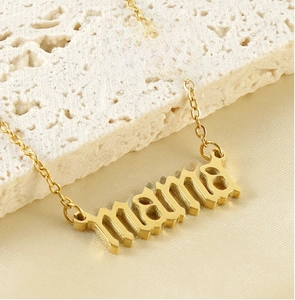Vue macro du collier avec pendentif MAMA doré sur pierre texturée et fond en soie