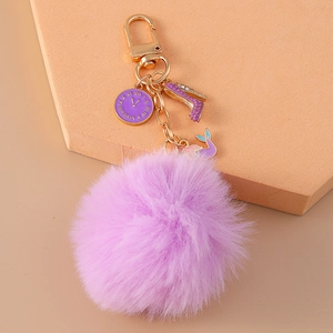 Detail of purple faux fur keychain with gold clock, heel and mermaid tail charms