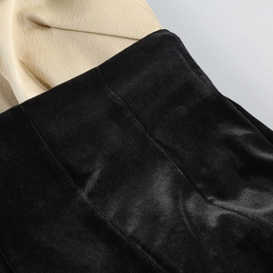 Détail macro montrant le contraste entre velours noir et tissu texturé beige cousu