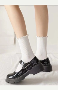 Detail weißer Rüschensocken kombiniert mit glänzend schwarzen Mary-Jane-Schuhen