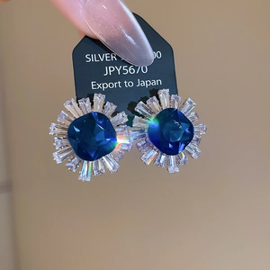 Detailed close-up of blue sunflower earrings with square zircon and silver base