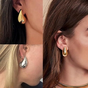 Detailed close-up showing golden and silver hollow teardrop earrings on the ear