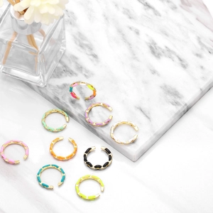Macro shot of colorful enamel link rings with micro-set zircon details on marble surface