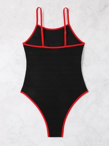 Detail of red and black one-piece swimsuit with ribbed texture on marble background