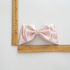Detailed view of pink satin bow hair clip size measuring 15cm with measurement scale