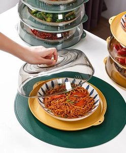 Macro detail of stackable clear food covers with yellow base lifting to show noodles