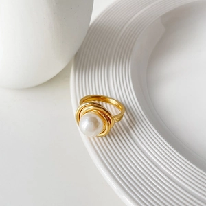 Bague élégante en acier titane doré avec grande perle blanche sur plat en céramique