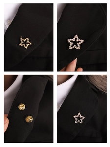 Detailed close-up of gold star brooch with pearls and rhinestones on a black suit lapel