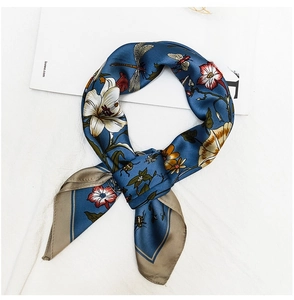 Macro view of blue silk scarf featuring floral lily prints and dragonfly details