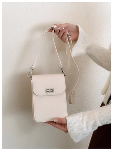 Close-up of a mini cream leather crossbody phone bag with adjustable strap and gold buckle