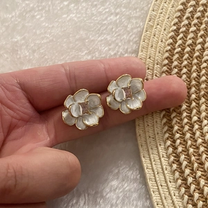 Vintage enamel camellia earrings with pink zircon and gold trim on white fabric