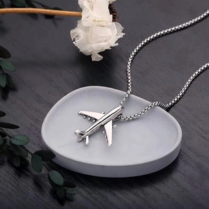 Silver airplane pendant necklace for kids on a minimalist grey display tray