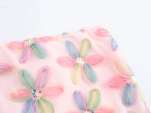Detailaufnahme von 3D-Netzblumen mit goldenen Pailletten auf dem rosa Stoff des Rocks