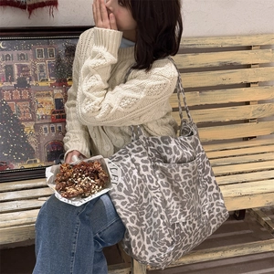 Detail of grey leopard print canvas tote bag with side pocket held by a model