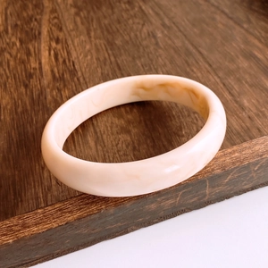 Détail d'un bracelet en résine crème avec texture marbrée brune sur bois