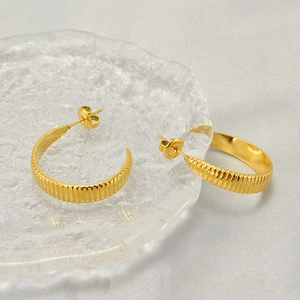 Classic gold stainless steel geometric hoop earrings with textured finish on glass plate