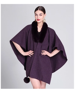 Detailed close-up of dark purple knit poncho featuring plush faux fur collar and hem tassels