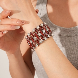 Dettaglio del bracciale elastico vintage con strass rossi e trasparenti indossato al polso