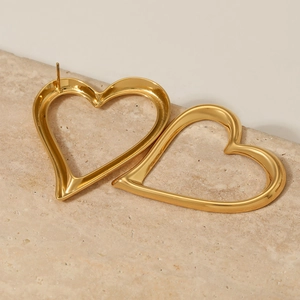 Polished gold heart hoop earrings in minimalist style on a decorative stone base