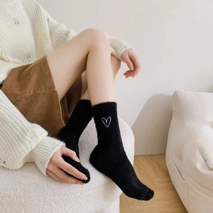 Detail of soft black coral fleece sock with white heart pattern and plush texture