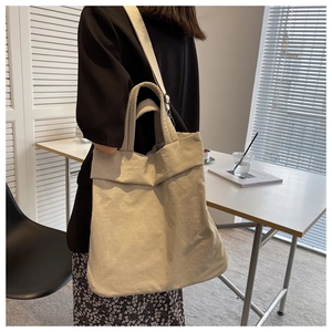Detail of a large beige nylon tote bag with wide strap for shoulder or crossbody wear