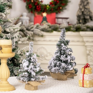 Close-up of two mini flocked Christmas trees with snow effect and burlap wrapped bases