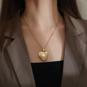 Elegant gold heart locket necklace with vintage floral engraving worn by a female model
