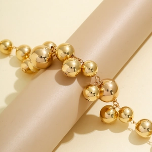 Detail showing the glossy gold metal beads and intricate pattern of the choker necklace