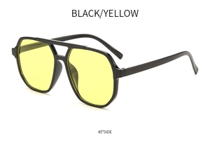 Detail shot of oversized double bridge sunglasses with black frames and yellow lenses