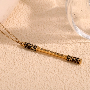 Macro detail of the golden Ruyi Jingu Bang pendant with black cloud patterns and engraving