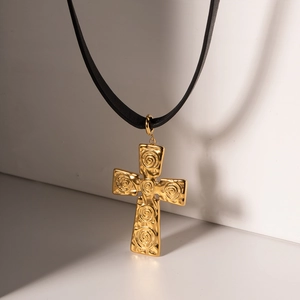 Détail d'un pendentif croix en or 18k avec texture martelée et motifs de spirales