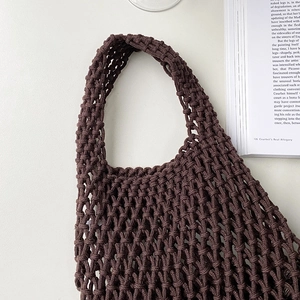 Detailed view of brown hand-woven cotton rope mesh tote bag on a minimalist white background