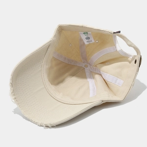 Detail of distressed beige cotton baseball cap interior with BSCI and ISO certification labels