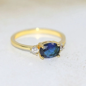 Elegant gold-plated ring featuring an oval blue zircon centerpiece and side crystal accents
