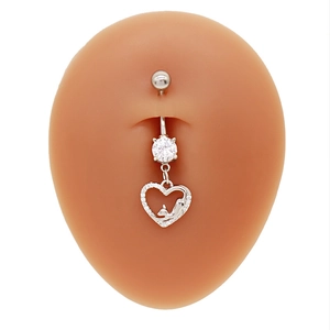 Détail d'un piercing de nombril coeur argenté avec gemmes claires sur un modèle