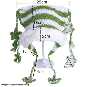 Detail view of handmade knitted cat ear hat with green stripes and floral tassels