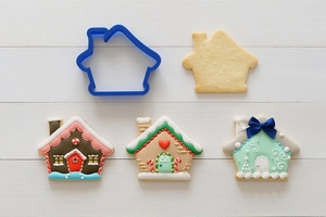 Detail showing blue plastic house cookie cutter and decorated gingerbread house treats