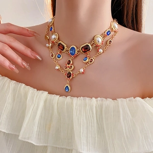 Detailed close-up of vintage gold necklace with multi-colored stones and faux pearls