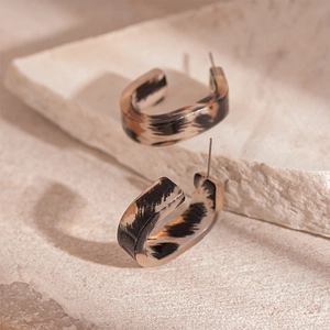 Detailed view of leopard print resin C-shaped earrings on a natural stone surface