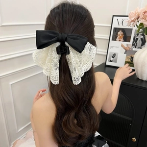 Close-up of black satin bow hair claw clip with delicate cream lace on wavy hair