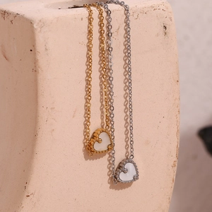 Détail de colliers cœur en or et argent avec incrustation en nacre sur un pot en céramique