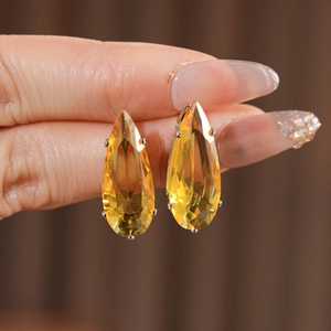 Macro shot of yellow teardrop-cut zircon earrings with silver four-prong settings