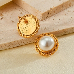 Detail of gold-plated pearl earrings showing woven chain texture and smooth white pearls