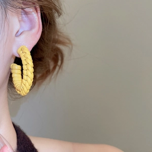 Detail of yellow woven leather hoop earrings shown worn on model with clean focus