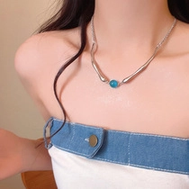Close-up of minimalist silver necklace with blue gemstone on female model collarbone